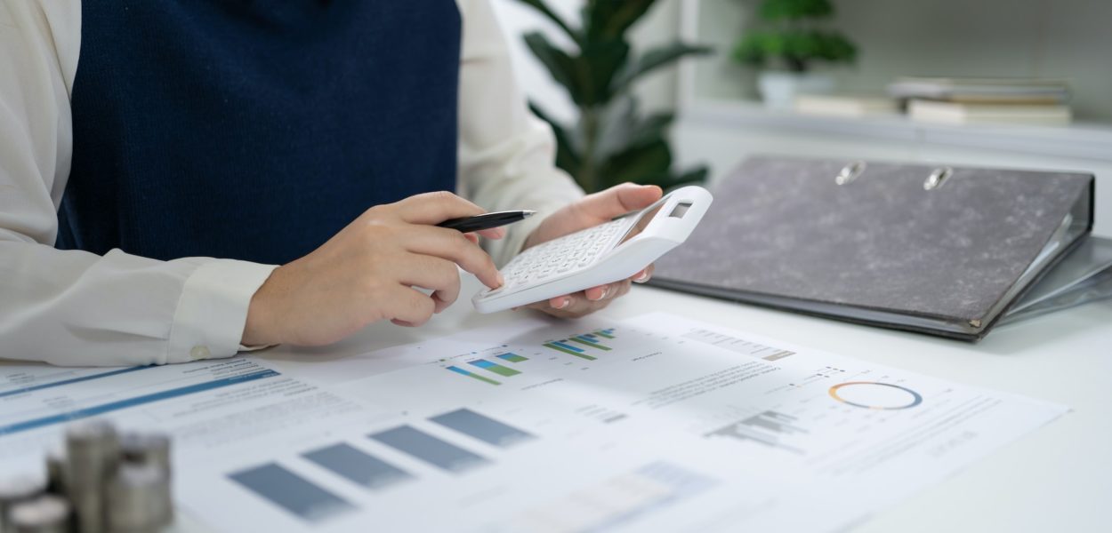 Businesswoman Accountant analyzing investment charts Invoice and pressing calculator buttons